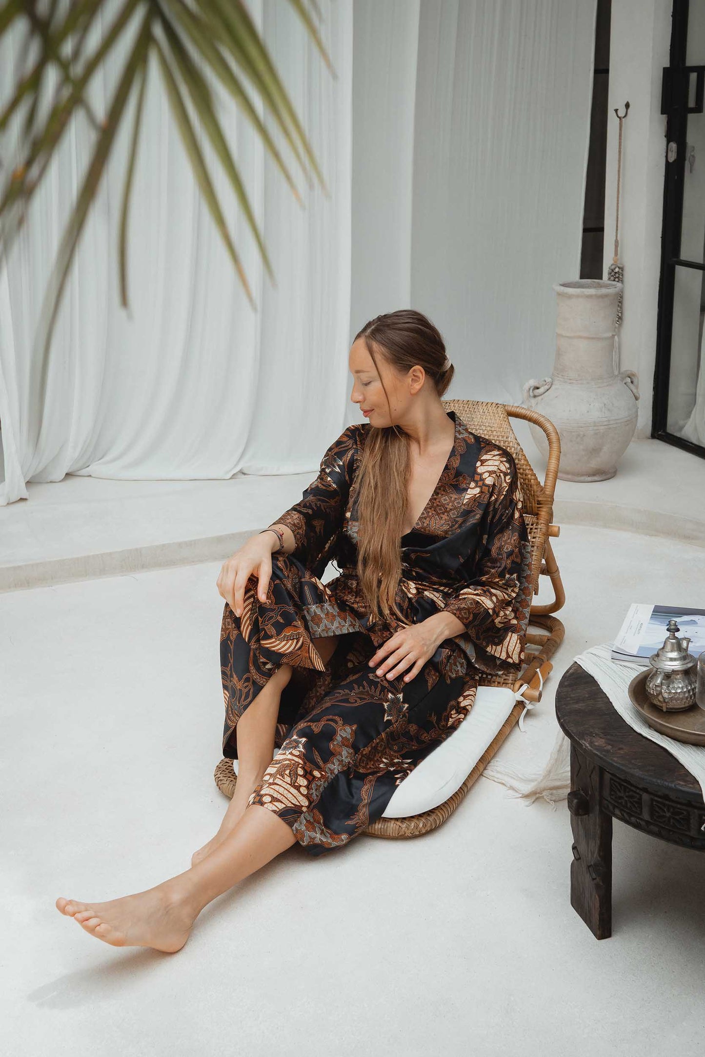 Woman sitting in a long satin dressing gown handmade in Bali.